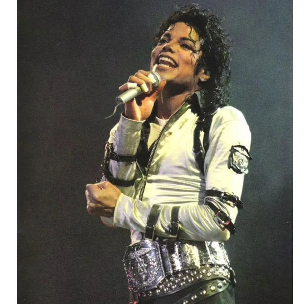 Person in a white jacket with black accents holding a microphone against a dark background