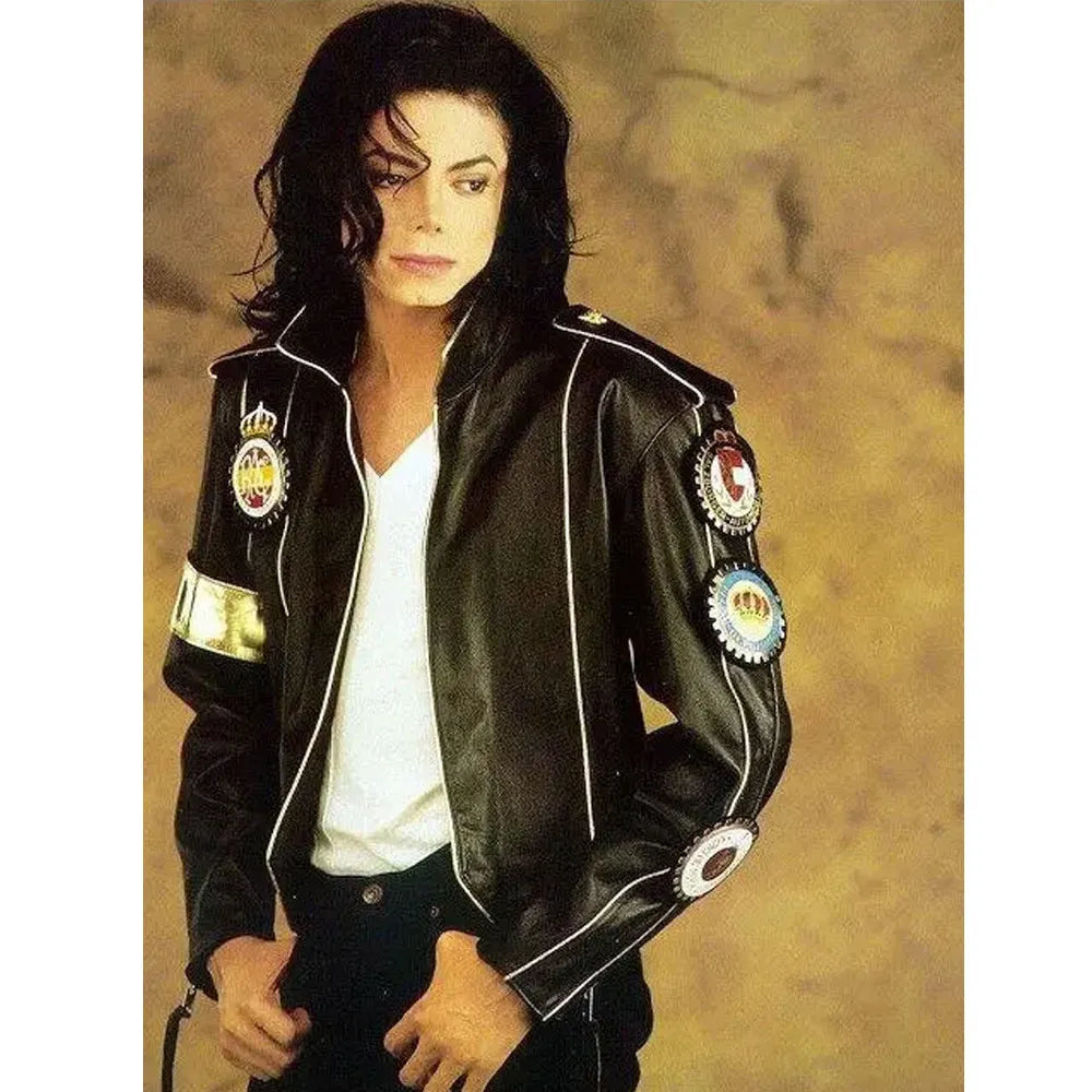 Person wearing a black leather jacket with decorative patches on a beige background
