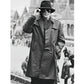 Person wearing a trench coat and hat in a black and white photo