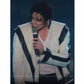 Person wearing a white jacket with black accents, holding a microphone against a dark background