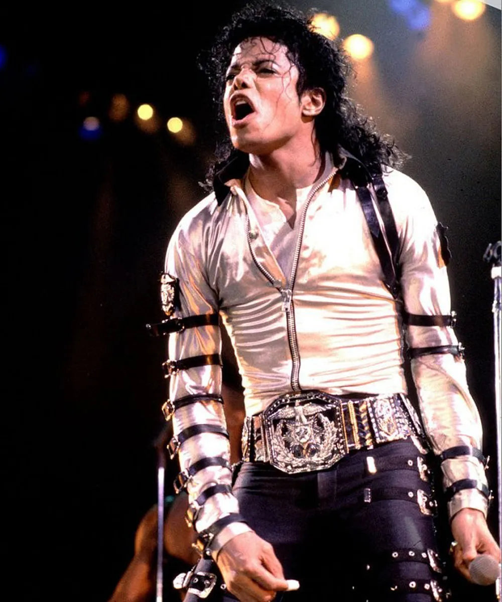 Person wearing a white shirt with black straps and a decorative belt on a dark background